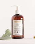 Lifestyle shot of Erbaviva Baby Body Wash (8 oz) with green leaves and small daisy flowers in the background