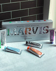 Lifestyle shot of Marvis Flavor Collection Gift Set box and tubes - Includes 25 ml each of: Amarelli Licorice, Aquatic Mint, Cinnamon Mint, Classic Strong Mint, Ginger Mint, Jasmine Mint and Whitening Mint shown with box