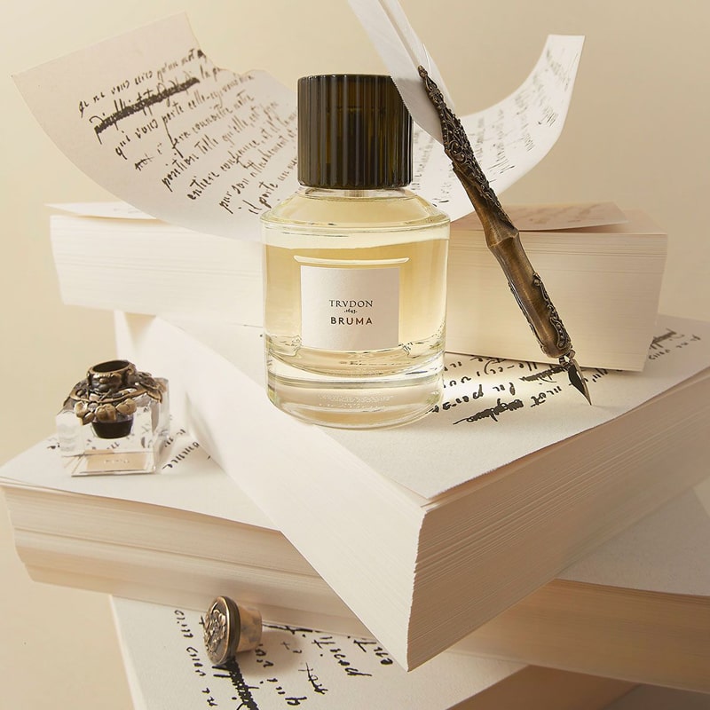 Lifestyle shot of Trudon Bruma Eau de Parfum (100 ml) sitting on stacks of paper with quill pen and ink and handwritten papers