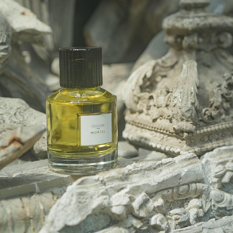 Lifestyle shot of Trudon Mortel Eau de Parfum (100 ml) sitting among ornamental pieces of architecture