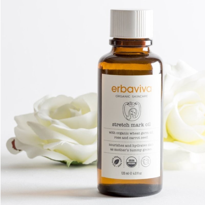 Lifestyle shot of  Erbaviva Stretch Mark Oil (4 oz) with white roses in the background