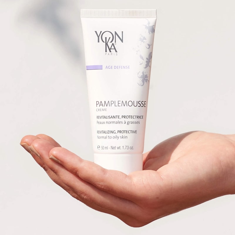 Close up of model holding Yon-Ka Paris Pamplemousse Creme PNG for Normal to Oily Skin (50 ml) in palm of hand