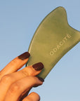 Close up of model holding Odacite Crystal Contour Gua Sha Green Adventurine Beauty Tool