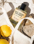 Lifestyle shot of Bastide Huile D'Aix Orange Blossom Bath Oil (250 ml) shown top view with sack of lemons in the foreground