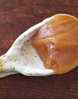 Activist Raw Manuka Honey 100+ MGO sample shown on spoon to show color and texture