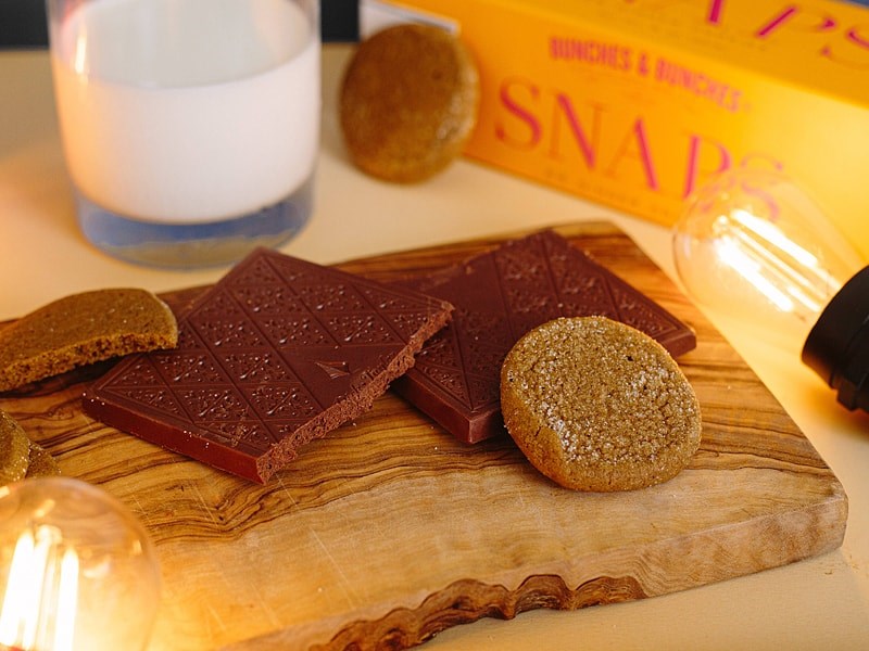 Dick Taylor Craft Chocolate Ginger Snap Milk Chocolate - product shown without packaging on wood plate with cookies