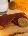 Dick Taylor Craft Chocolate Ginger Snap Milk Chocolate - product shown without packaging on wood plate with cookies