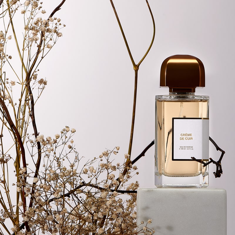 BDK Parfums Crème de Cuir Eau de Parfum (100 ml) bottle on pedestal with dried flowers and branches in the background