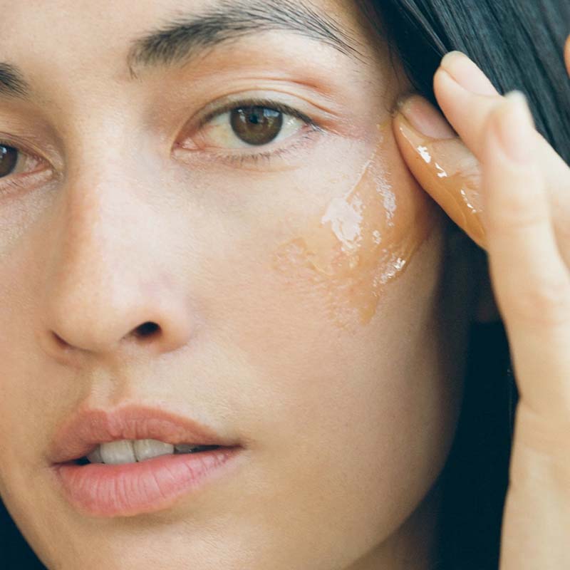 Close up of model applying Activist Manuka Honey Mask to cheek