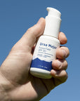 Lifestyle shot of Ursa Major Force Field SPF 30 shown in hand of model with blue sky in the background