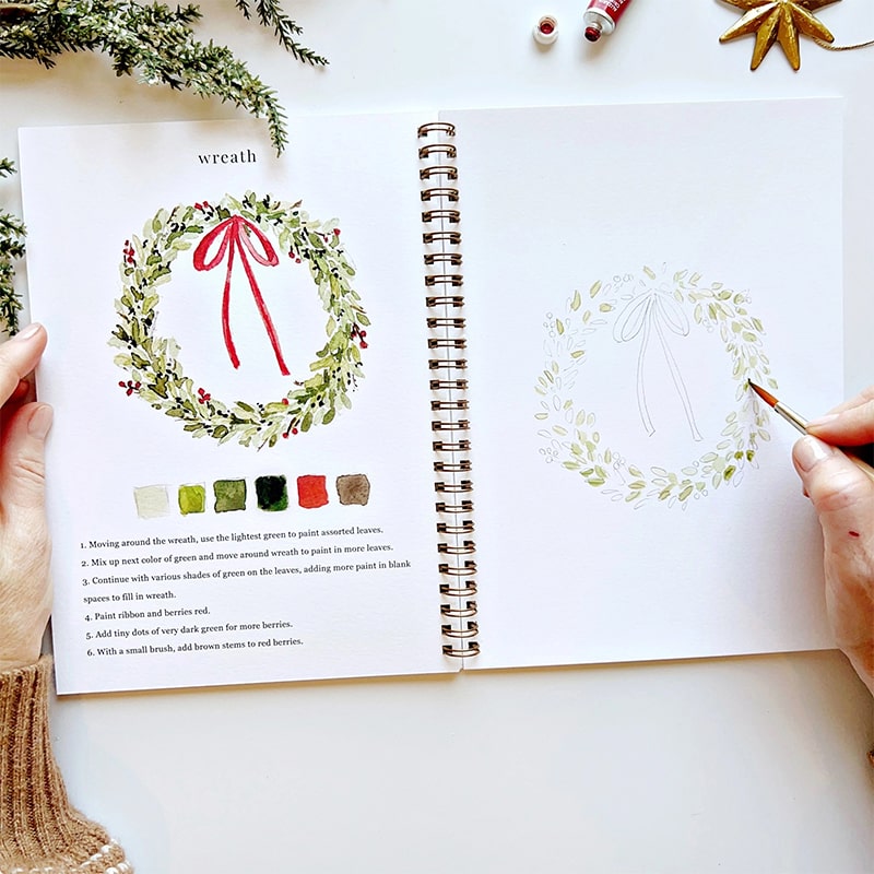 Emily Lex Studio Christmas Watercolor Workbook - model shown painting inside product