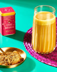 Lifestyle shot of Diaspora Co Chai Masala (1.59 oz) shown in tin with gold bowl showing Chai Masala powder and Chai Masala drink made in glass