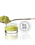 Kure Bazaar Matcha Lip & Nail Balm - product shown next to cap and spoonful of matcha powder on top