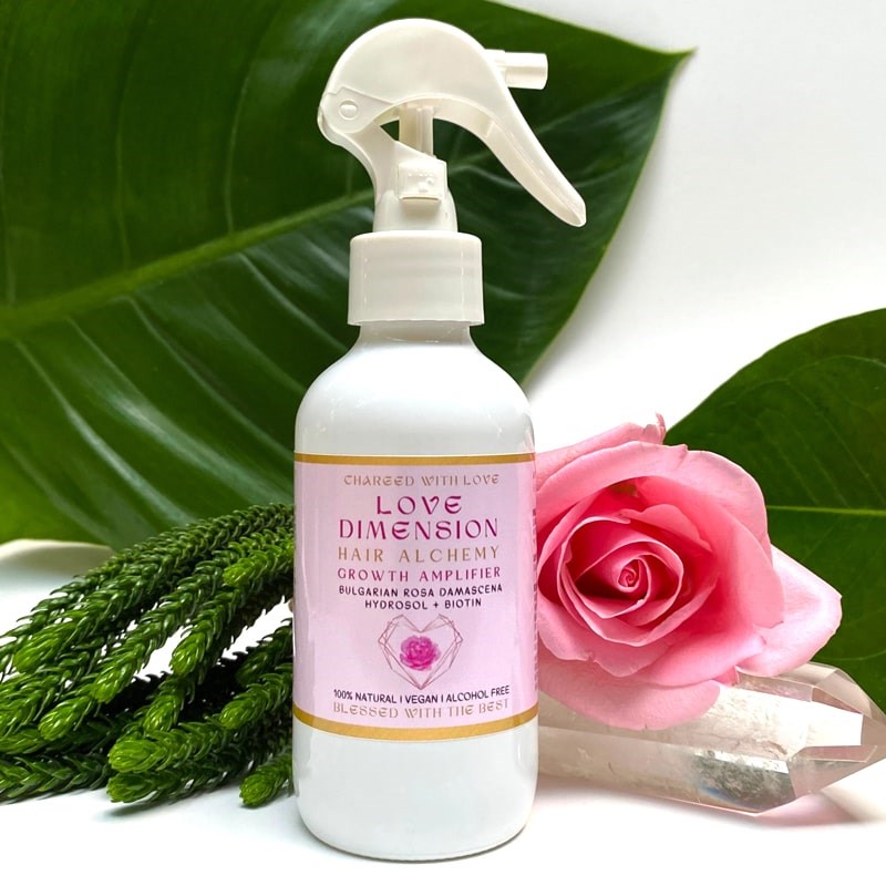 The Sacred Essence Love Dimension - Bulgarian Rose Hydrosol & Biotin - product shown in front of plants, flowers, and crystals
