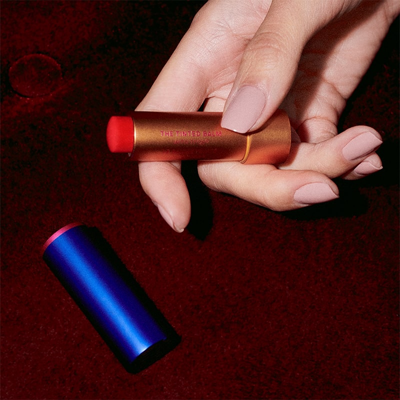 Augustinus Bader The Tinted Lip Balm - Shade 2 - model shown holding product and cap near by