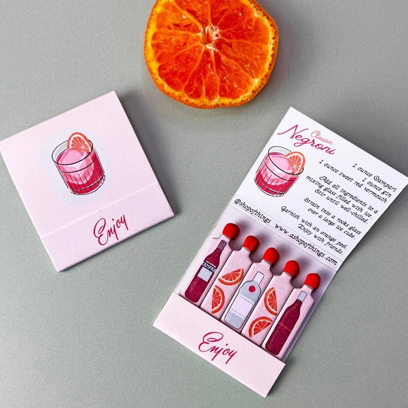 A Shop of Things Negroni Matches - product shown next to sliced orange and open matchbook