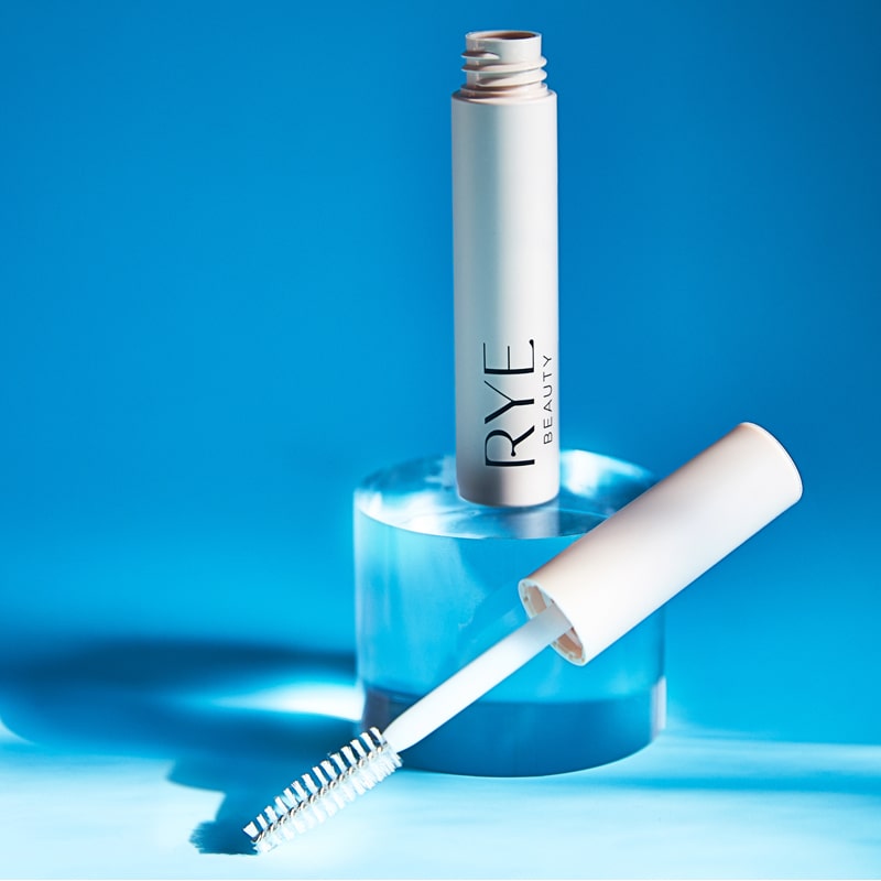 Lifestyle shot of Rye Beauty Brow Milk (6 ml) tube shown open with wand