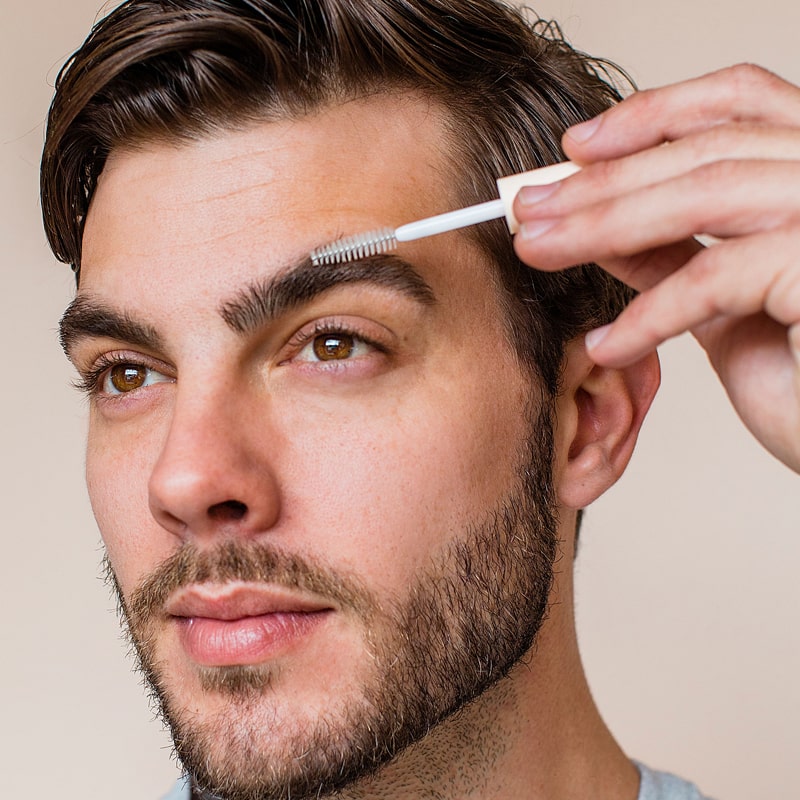 Close up of male model applying Lifestyle shot of Rye Beauty Brow Milk to eyebrow