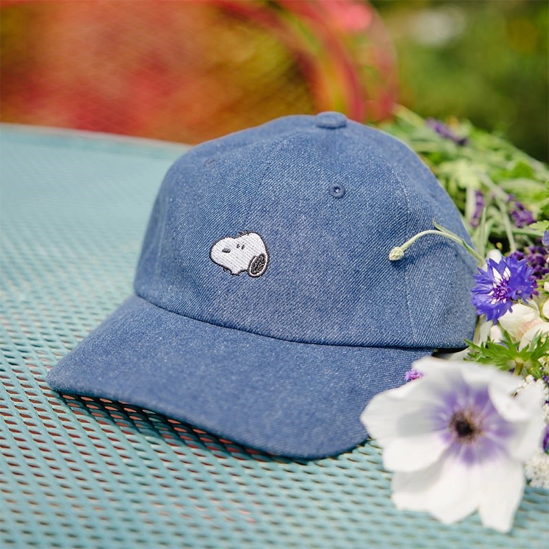 Three Potato Four 3P4 X Peanuts Snoopy Embroidered Denim Dad Hat - product shown on garden table with flowers