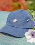 Three Potato Four 3P4 X Peanuts Snoopy Embroidered Denim Dad Hat - product shown on garden table with flowers