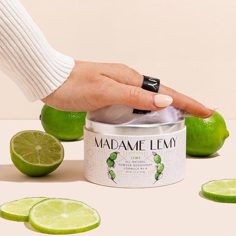 Madame Lemy All Natural Powder Deodorant - Lime - model shown holding puff in packaging surrounded by limes