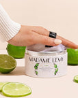 Madame Lemy All Natural Powder Deodorant - Lime - model shown holding puff in packaging surrounded by limes