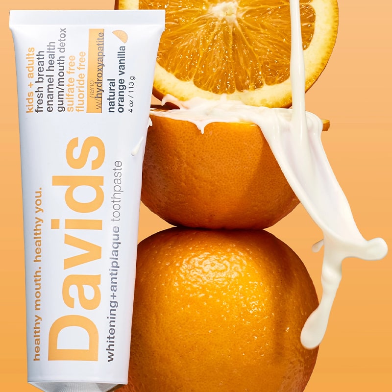 Davids Premium Toothpaste - Kids + Adults Nano-Hydroxyapatite Orange Vanilla - product shown next to oranges with cream flowing over them