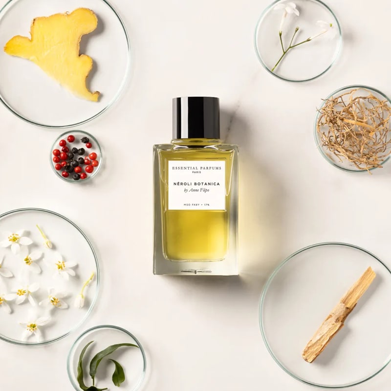 Lifestyle shot top view of Essential Parfums Neroli Botanica By Anne Flipo (100 ml) with neroli, ginger and other ingredients in the background