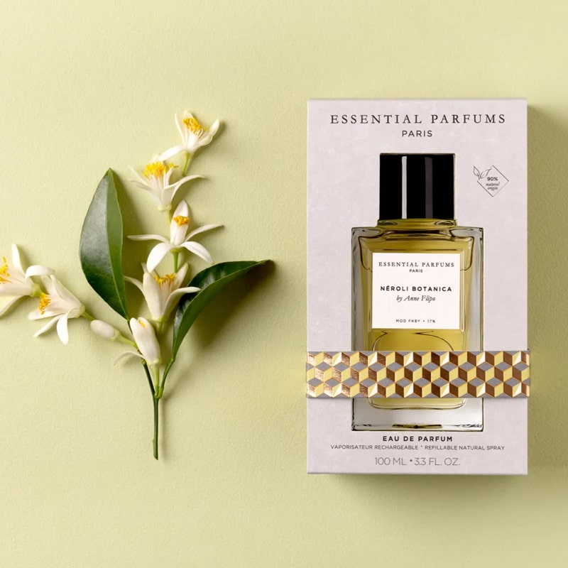 Lifestyle shot top view of Essential Parfums Neroli Botanica By Anne Flipo (100 ml) in box with Neroli flowers next to the box