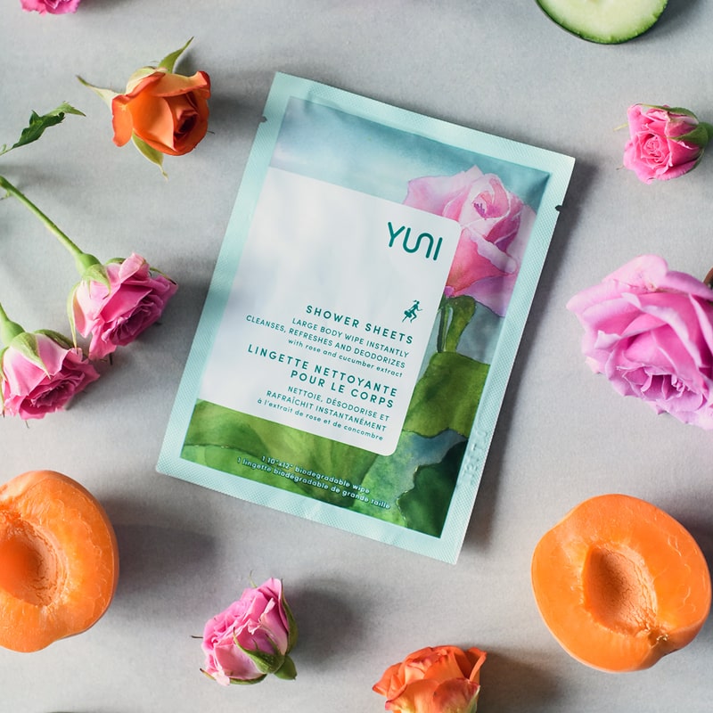 YUNI Beauty Yuni Rose Cucumber Shower Sheets Large Body Wipes - product next to flowers and fruit 