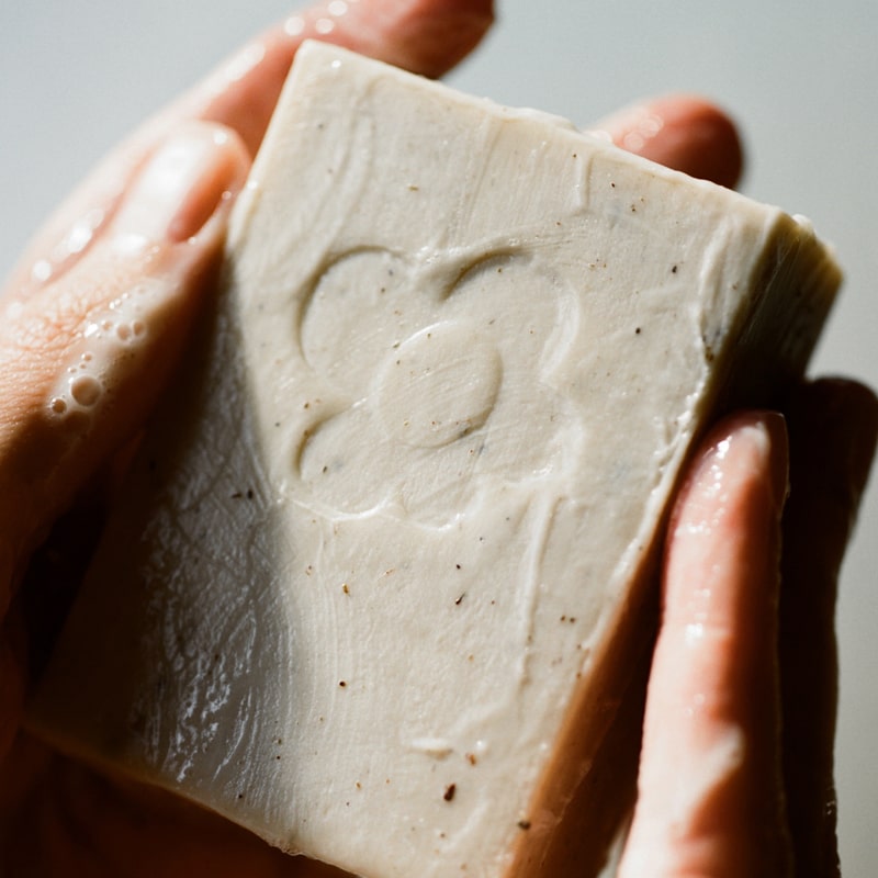 Close up of Activist A.M.S Manuka Botanical Soap Bar (4.23 oz) shown in hands with slight later