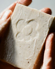 Close up of Activist A.M.S Manuka Botanical Soap Bar (4.23 oz) shown in hands with slight later