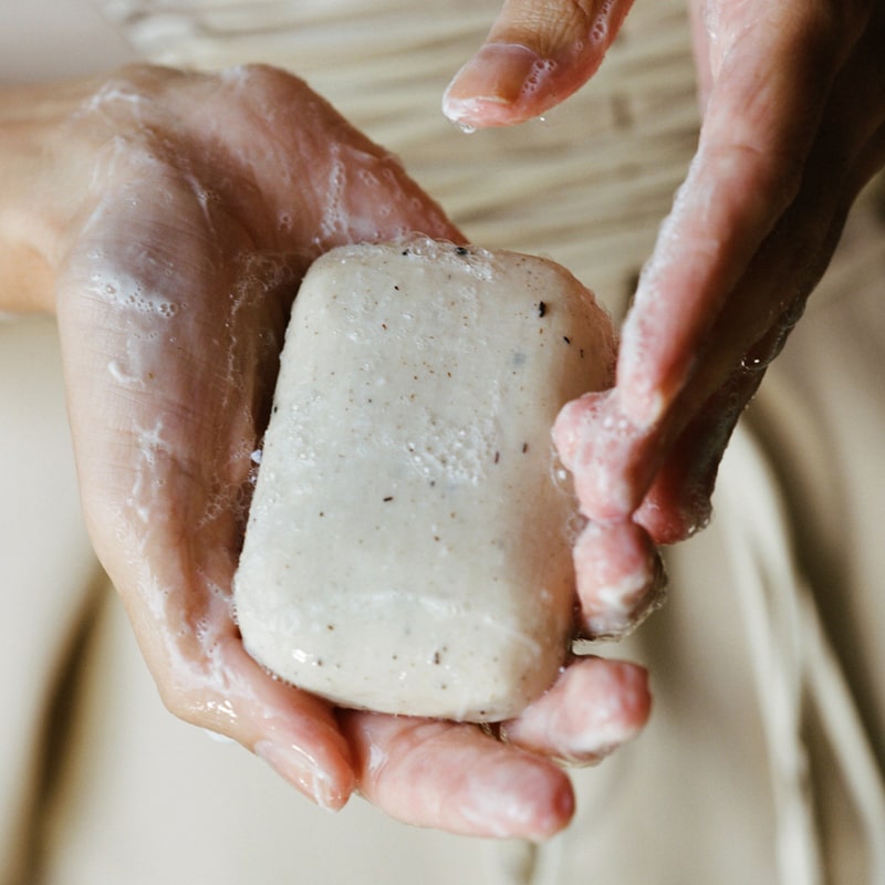 Close up of Activist A.M.S Manuka Botanical Soap Bar (4.23 oz) shown in hands with slight later