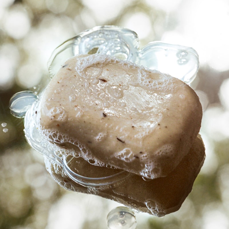 Close up of Activist A.M.S Manuka Botanical Soap Bar (4.23 oz) shown with soap suds on and around bar