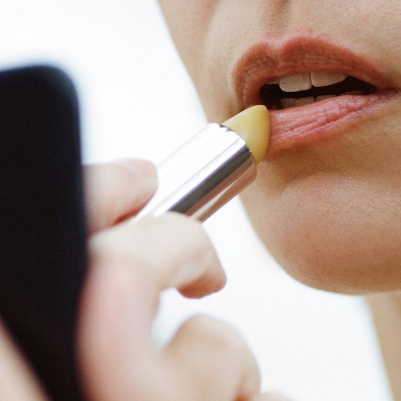 Close up of model applying Activist A.M.S Manuka Honey Lip Balm to lips