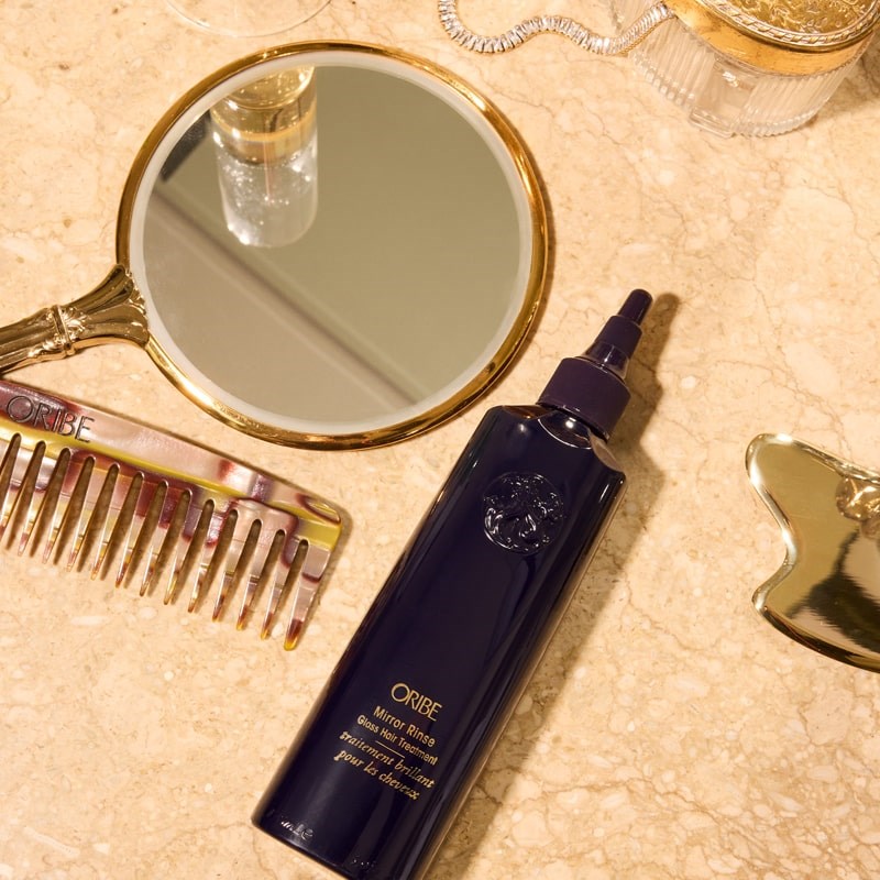 Oribe Mirror Rinse Glass Hair Treatment - product shown next to hair accessories