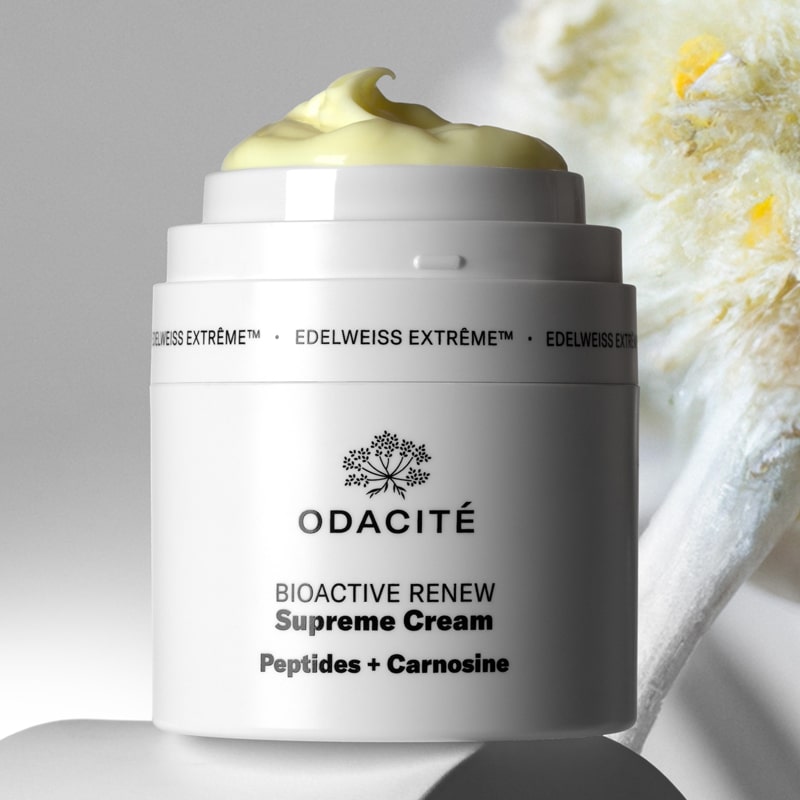 Lifestyle shot of Odacite Edelweiss Extreme Bioactive Renew Supreme Cream (50 ml) with top off showing cream at the top of the pump jar and edelweiss flower in the background