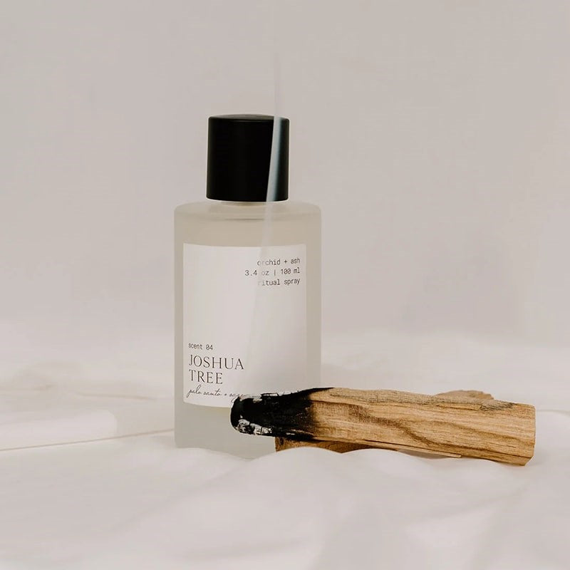 Orchid + Ash Joshua Tree Ritual Spray - product shown next to burning palo santo stick on fabric