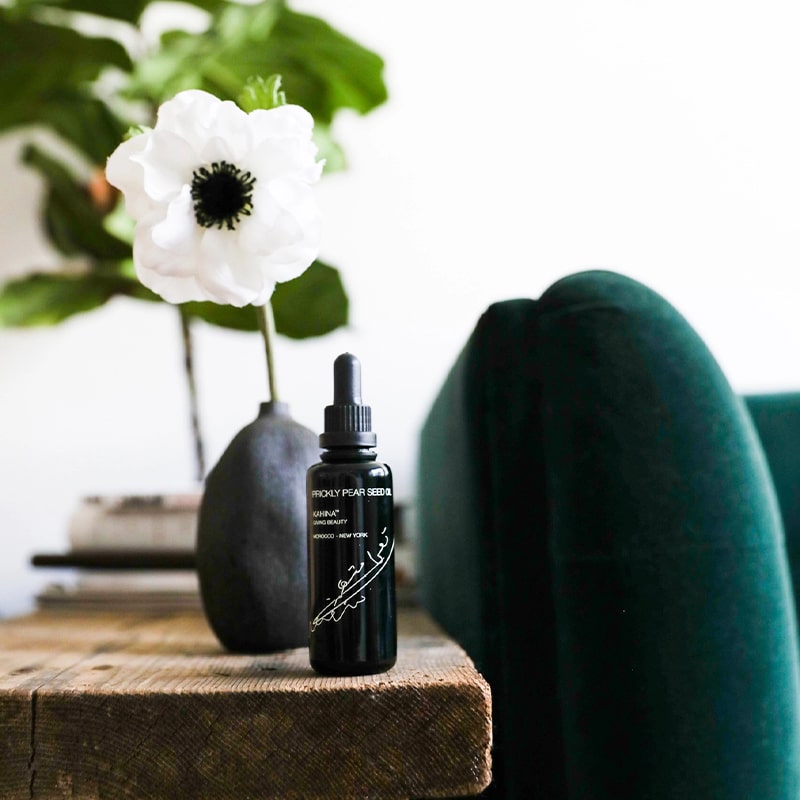 Kahina Giving Beauty Prickly Pear Seed Oil - product shown on table next to potter plant and chair