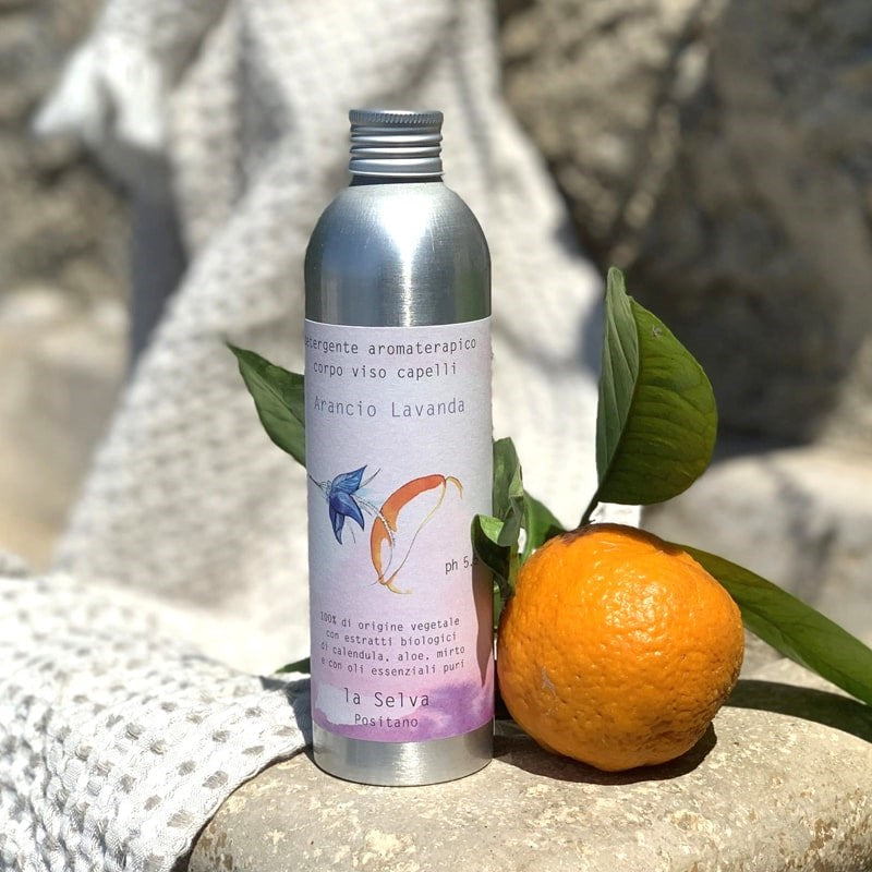 La Selva Positano Orange and Lavender Aromatherapy Cleanser - product shown next to orange sitting on rock with towel 