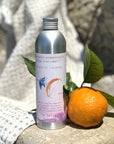 La Selva Positano Orange and Lavender Aromatherapy Cleanser - product shown next to orange sitting on rock with towel 