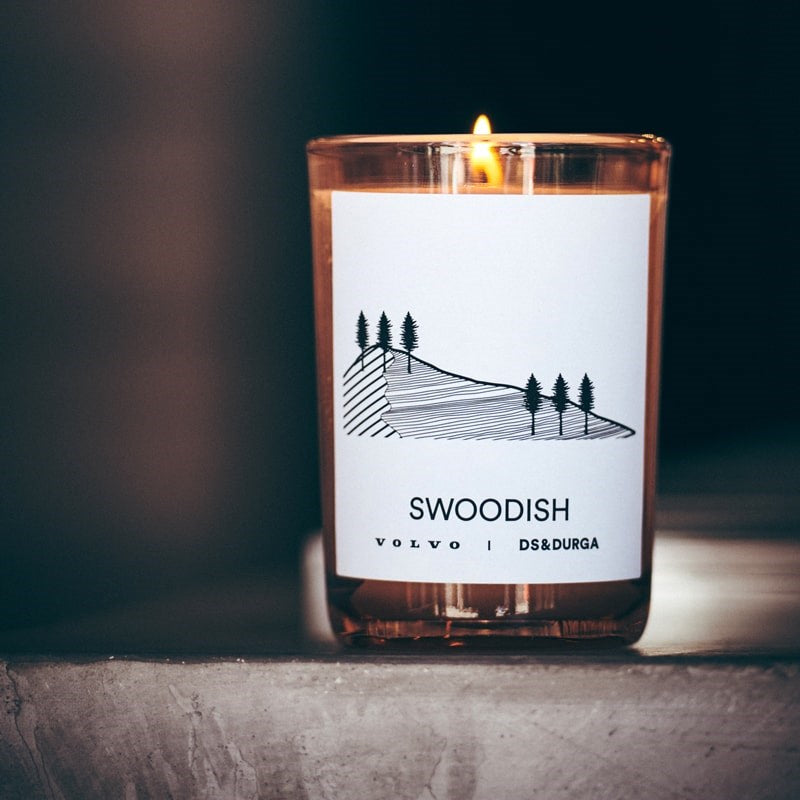 Lifestyle shot of D.S. &amp; Durga Swoodish Candle (7 oz) lit sitting on concrete table