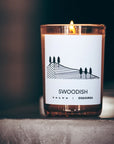 Lifestyle shot of D.S. & Durga Swoodish Candle (7 oz) lit sitting on concrete table