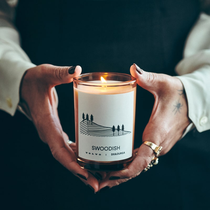 Lifestyle shot of D.S. &amp; Durga Swoodish Candle (7 oz) lit held in hands of model