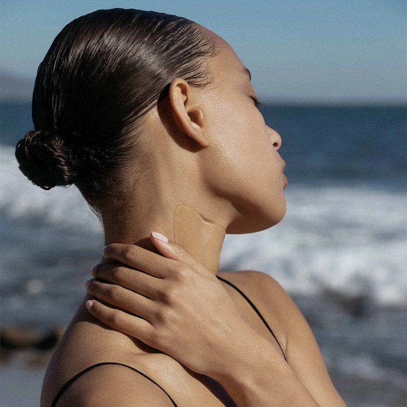 Ametta Skin Firming Neck Mask - model shown wearing product on neck at beach