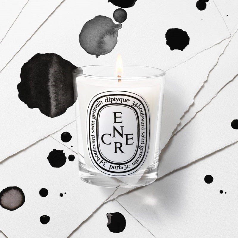 Diptyque Limited Edition Encre Candle (190 g) - product shown lit in front of paper with ink drops