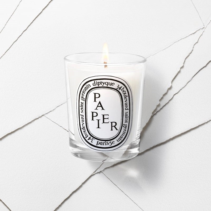 Diptyque Limited Edition Papier Candle - product shown lit on top of paper sheets