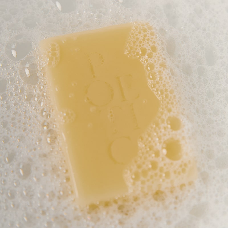 Poetica Lemon Myrtle & Cardamom Botanical Garment Bar Soap (3 oz) - Product shown in water with soap bubbles