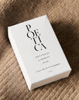 Poetica Lemon Myrtle & Cardamom Botanical Garment Bar Soap (3 oz) - product packaging shown on fabric