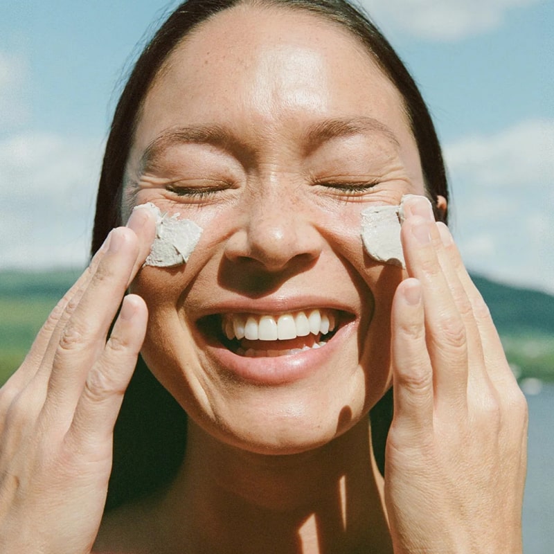 Ursa Major Green Slate Mineral Polish - model shown putting product on face